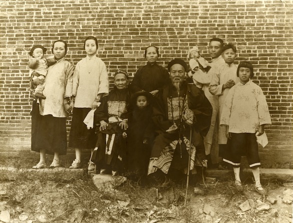 Family photograph.  Frank, Mary and Baby Wing pose in 1926 China with Frank's parents and family.  May is third from the left; Frank, holding baby Wing, is third from the right. 